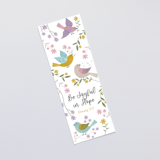 A bookmark with the phrase 'Be Joyful in Hope' surrounded by colorful bird illustrations and floral designs, printed on white card stock with a laminated finish.